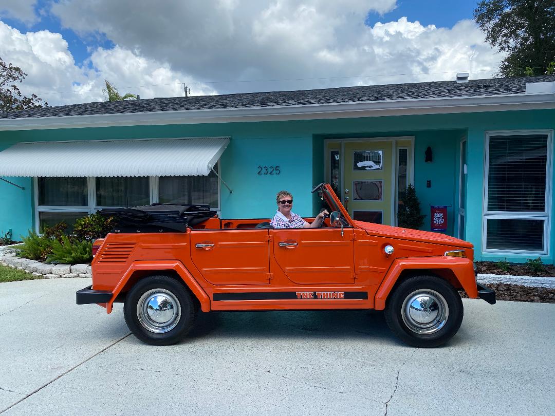 A man in an orange truck parked outside of a house.